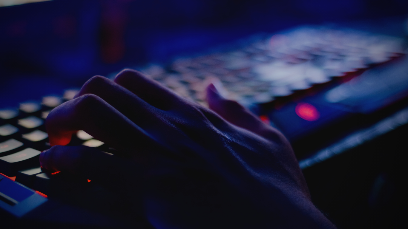 Mãos digitando em teclado iluminado em azul